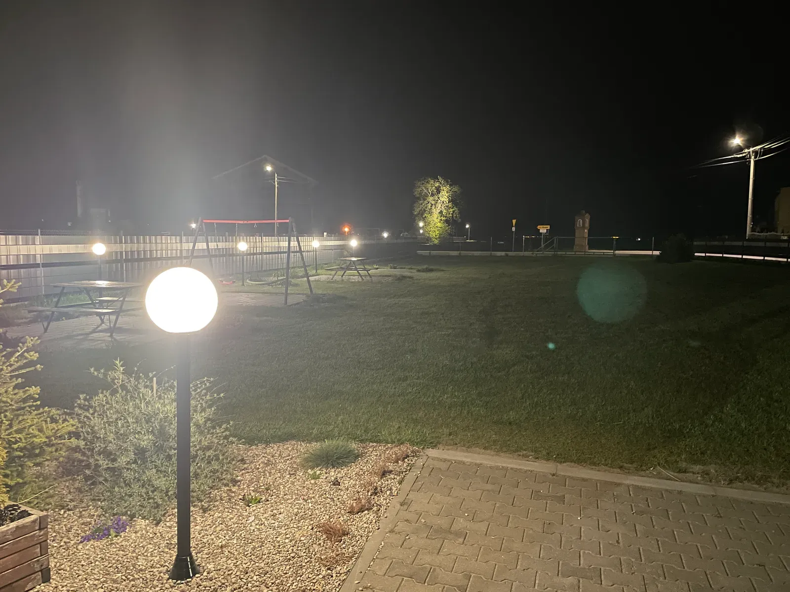 Ogród i plac zabaw przy sali w wieczornym oświetleniu