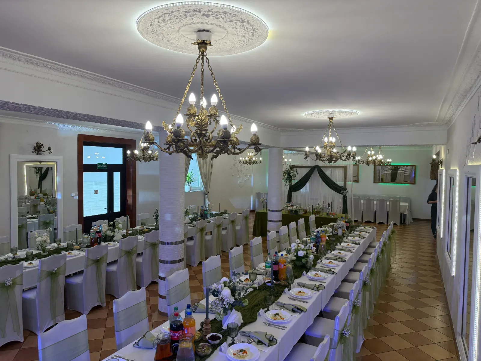 Widok spod żyrandoli na stoły z zielonymi bieżnikami