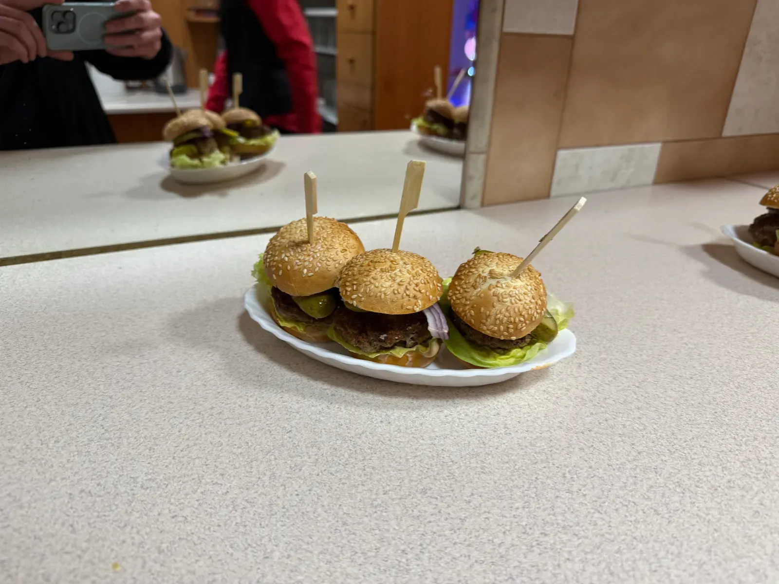 Trzy mini burgery na patyczkach podane na białym półmisku