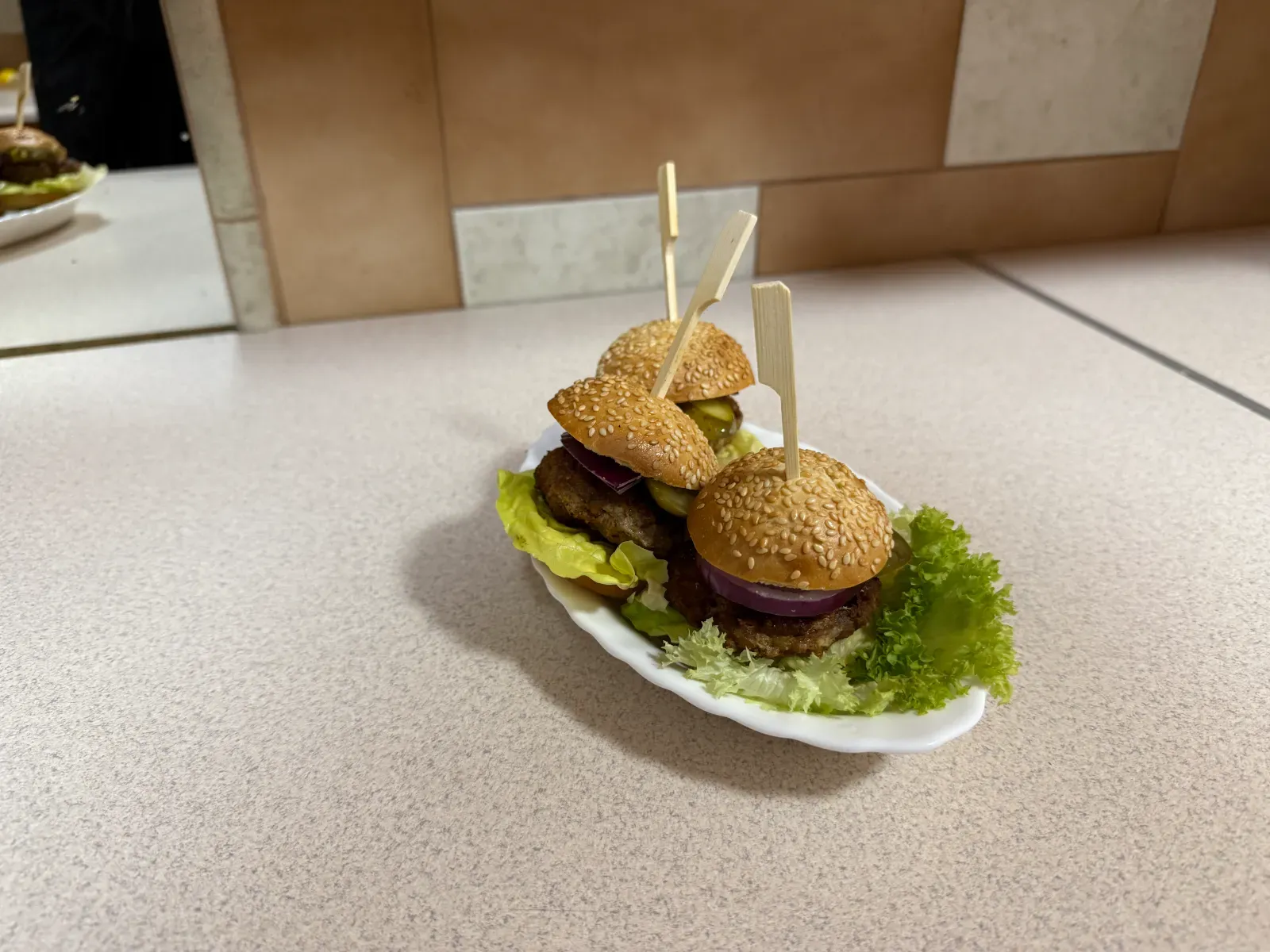 Mini burgery z ogórkiem i czerwoną cebulą na listkach sałaty