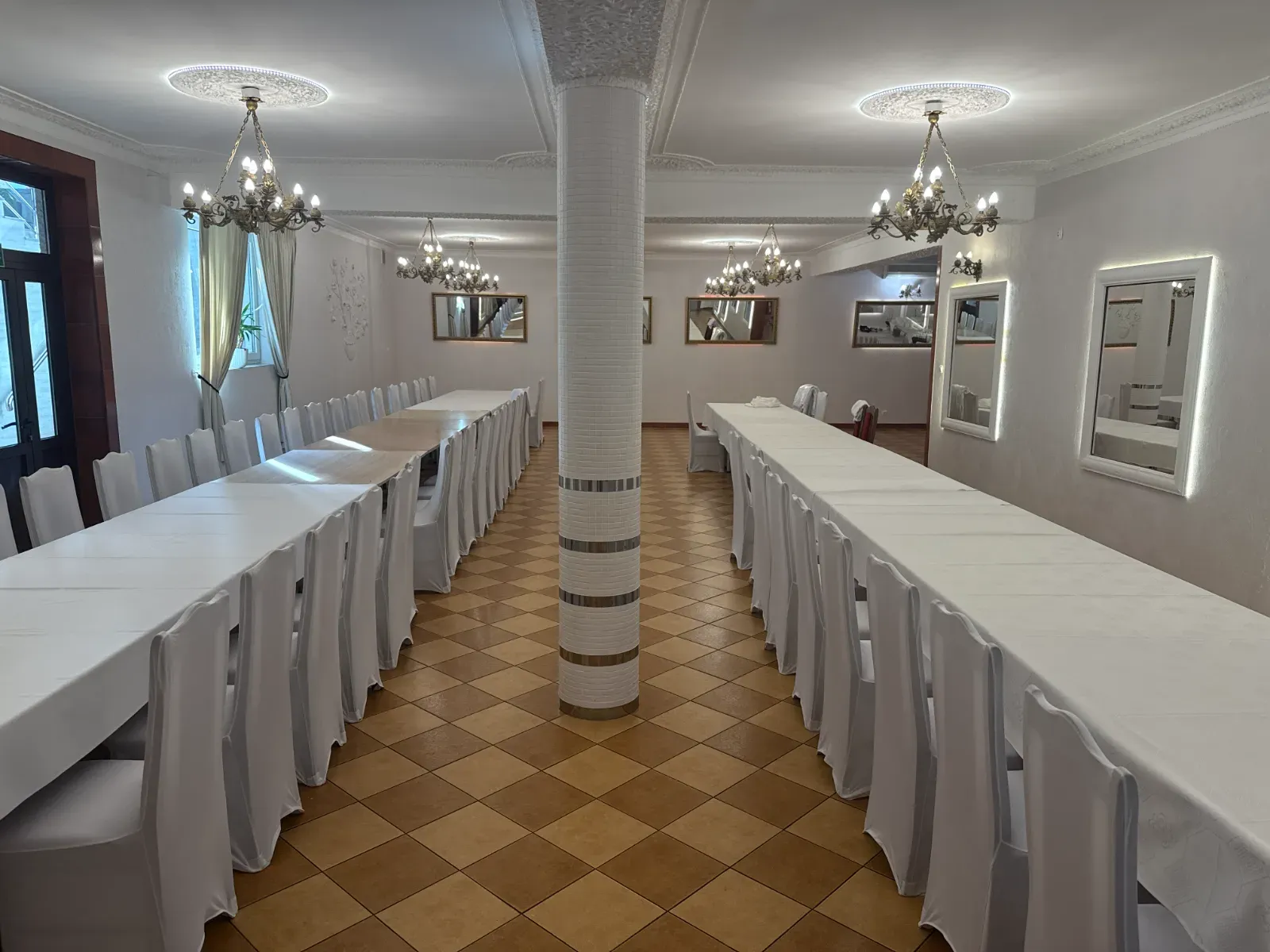Pusta sala z dwoma rzędami stołów nakrytych białymi obrusami