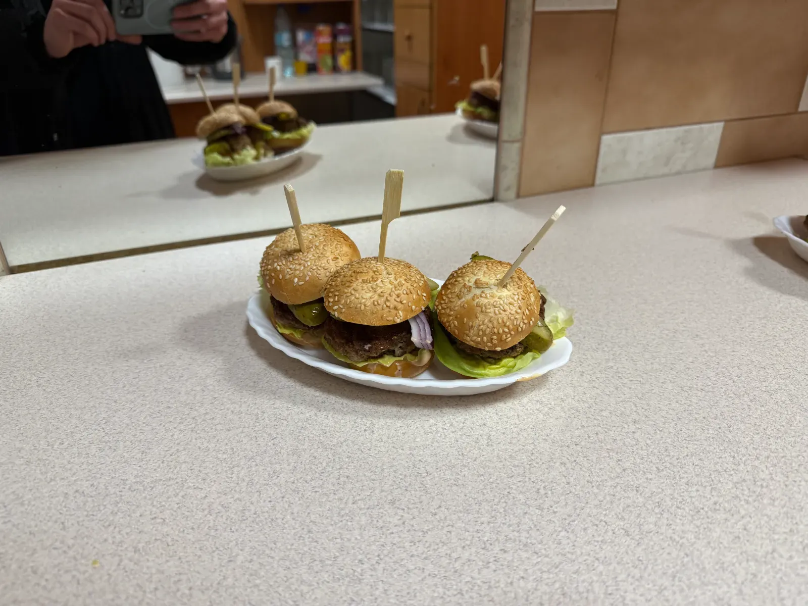 Półmisek mini burgerów na kuchennym blacie przed lustrem