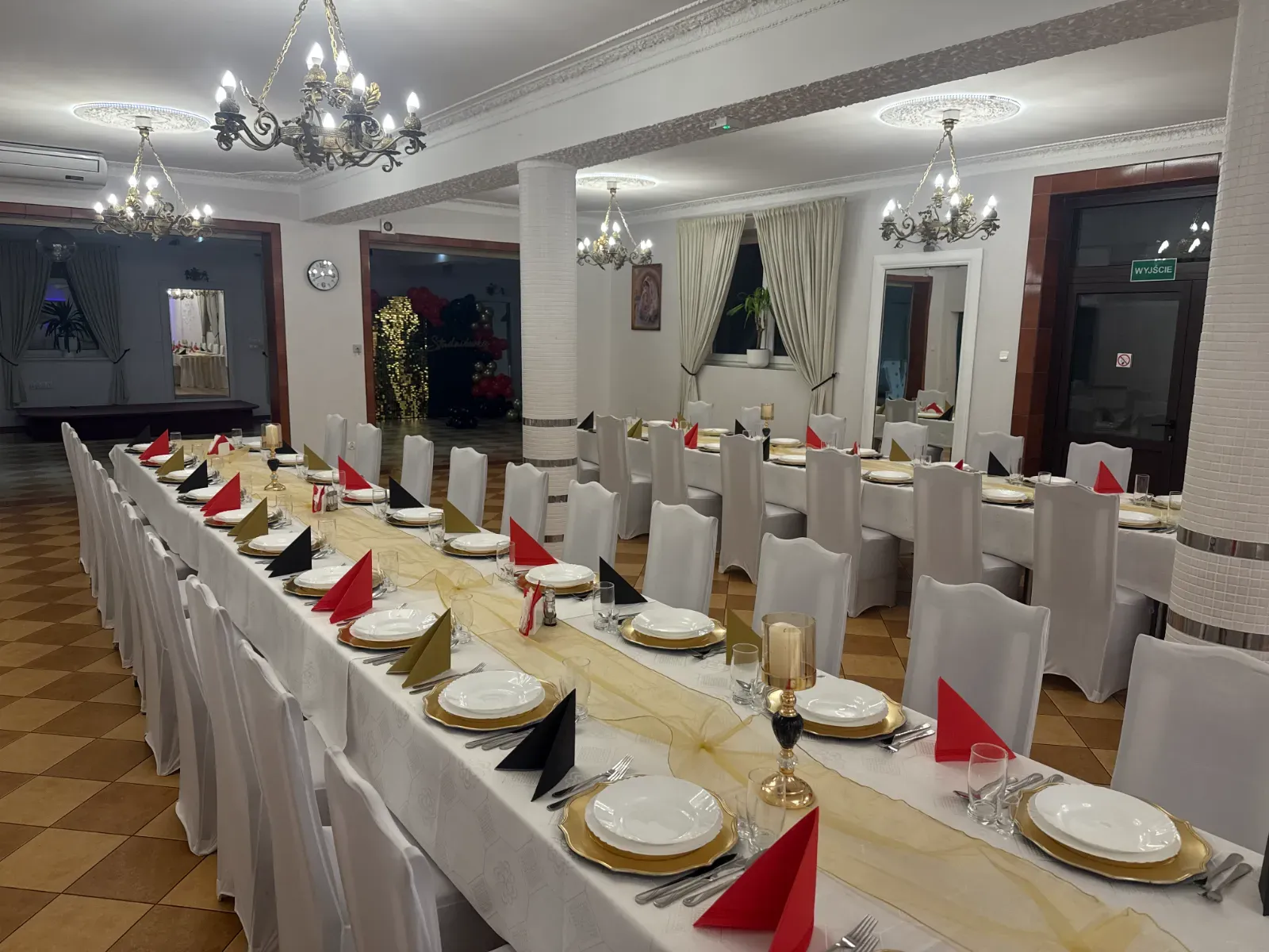 Stół nakryty w czerwieni i czerni ze złotym bieżnikiem